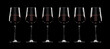 Silhouettes of six wine glasses with red wine on black background