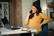 © JustLife - Beautiful pregnant woman working on laptop. Young businesswoman talking to the phone..