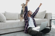 © ASDF - happy guy exults with his dog sitting near the sofa in the living room.