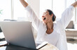 © BullRun - Happy woman with laptop raising arms in victory gesture