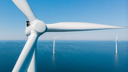 Windmill turbines in the ocean with a blue sky