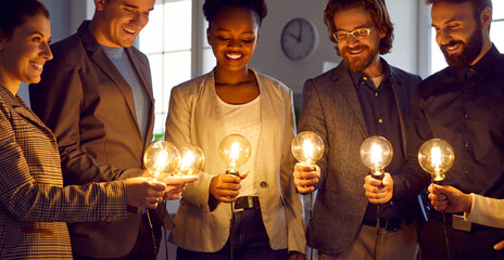 Business people look at bright idea light bulbs. Smart multiracial team share professional insights, solve problems, make plans for future, develop strategy for positive changes, work on group project