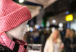 Einkaufen im Winter: Nahaufnahme einer Schaufensterpuppe mit roter Wollmütze und modischen Schal in einer abendlichen Einkaufsstraße mit Menschen im verschwommenen Hintergrund, viel Copy Space ..