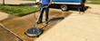Leinwandbild Motiv man pressure washes driveway with pressure washer surface cleaner 
