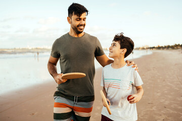 Father and son having fun on the beach during summer vacation playing beach tennis