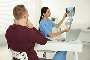 Canvas Print - Doctor with neck MRI images consulting patient in clinic, space for text