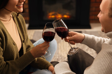 Wall Mural - Happy lovely couple with glasses of wine spending time together near fireplace at home, closeup