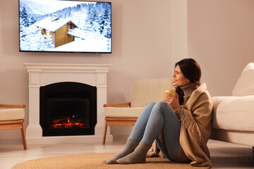 Sticker - Young woman with cup of tea relaxing on floor near fireplace at home