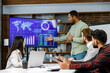 © YURII MASLAK - Motivated african american businessman having business meeting with managers, negotiating, using presentation tv with statistics, charts, big data. Digital entrepreneurs work on an e-commerce project.