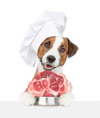 Poster - jack russell terrier puppy wearing chef's hat holds bowl of raw meat and looks above empty white banner. isolated on white background