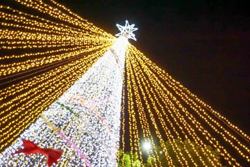 Wall Mural - Look up view blurred and bokeh of Christmas tree lighting on night time background.