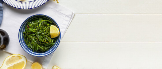 Bowl with healthy seaweed salad and lemon on white wooden background with space for text