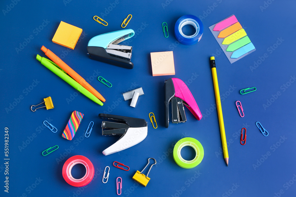 Set of stationery with staplers on blue background