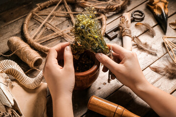 Young witch performing ritual at wooden table