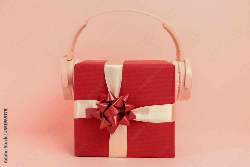 Headphones with Christmas gift on pink background