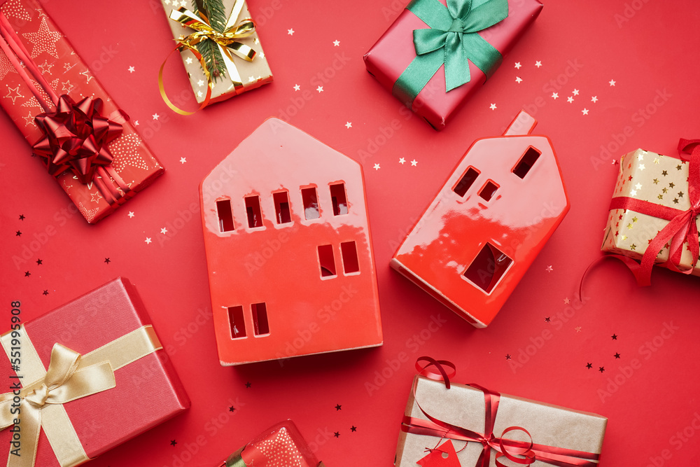 House shaped candle holders with Christmas gifts on red background