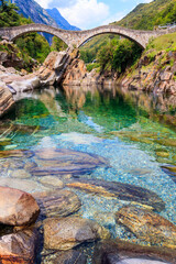 Ancient double arch stone Roman bridge (Ponte dei Salti) over the clear water of the Verzasca river in Lavertezzo ,Verzasca Valley, Ticino Canton, Switzerland