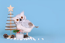 Seasonal Christmas Decoration With Snowy Owl, Wooden Tree, Candle, Pine Cones And Snowballs On Blue Background With Copy Space