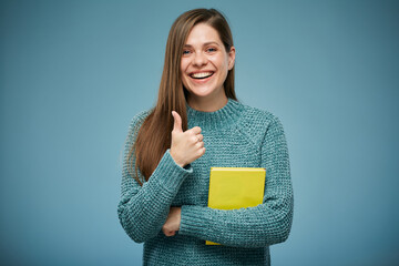 Wall Mural - Smiling woman holding yellow book showing thumb up. Isolated advertising portrait.