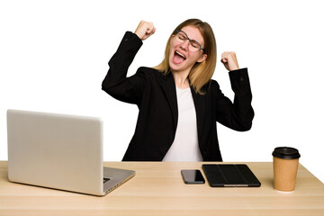 Wall Mural - Young business caucasian woman working on her workplace cutout isolated raising fist after a victory, winner concept.