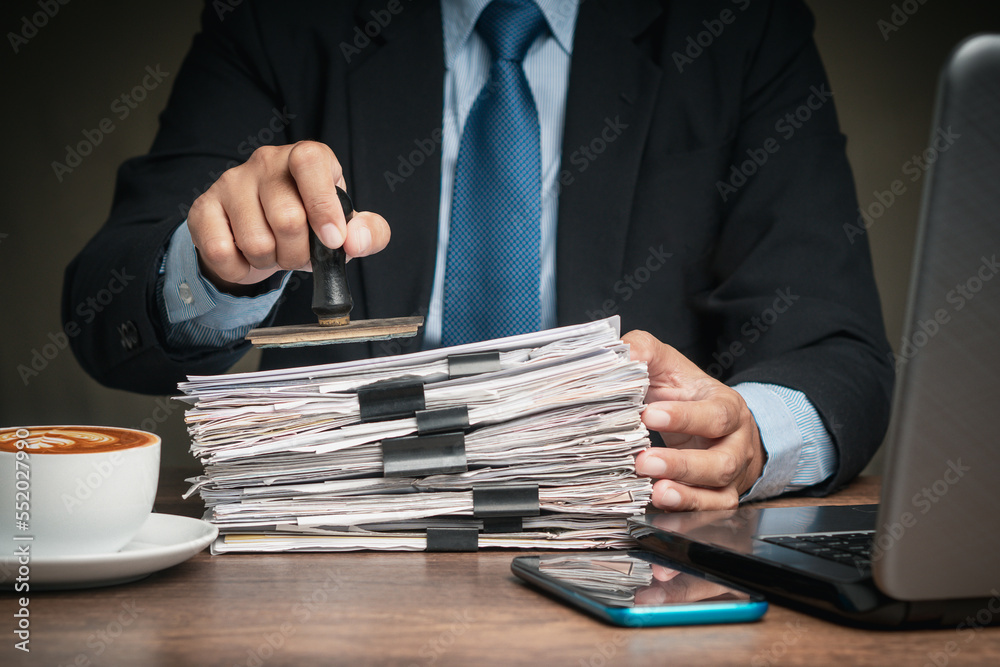 Businessman stamped for approved documents while sitting at the table in the office
