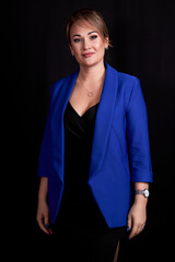 Wall Mural - caucasian adult woman in a blue jacket stands on a black background