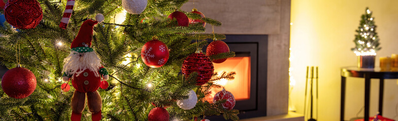 Wall Mural - Christmas banner. Xmas tree decoration and lights close up, burning fireplace background.