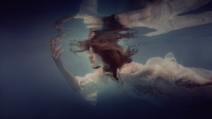 Wall Mural - Portrait of a girl with dark hair in a lace dress underwater