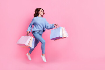 Poster - Full body profile portrait of overjoyed cheerful lady hold packages jump rush empty space isolated on pink color background