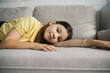 © LIGHTFIELD STUDIOS - brunette girl in beaded bracelet lying on cozy couch and looking at camera