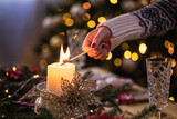 Fototapeta Tulipany - Young girl lighting a candle for Christmas dinner