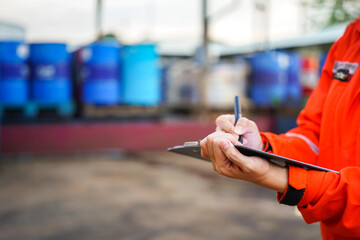 Wall Mural - a safety office is writing on paper clipboard during perform safety audit with chemical storage in f