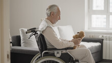 Lonely Old Man In Wheelchair Holding Teddy Bear, Missing Family In A Retirement Home