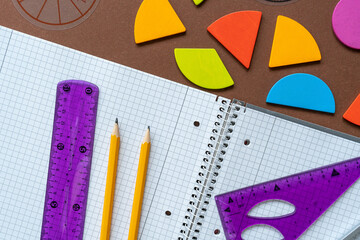 Wall Mural - Set of supplies for mathematics and for school. Fractions, rulers, pencils, notepad on brown background. Back to school, fun education concept. School supplies on the table