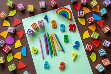 Wall Mural - Wooden kids toys on colourful paper. Educational toys, blocks, pyramid, pencils, numbers, rainbow. Toys for kindergarten, preschool or daycare. Copy space for text. Top view. Back to school background