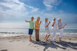 gruppo di 5 anziani al mare  giocano felici facendo il segno di 
