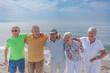 © alex.pin - gruppo di 5 anziani al mare  si abbracciano  felici - sullo sfondo si vede il cielo blu