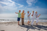 Fototapeta Miasto - gruppo di 5 anziani al mare  giocano felici facendo il segno di 