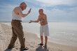 © alex.pin - coppia di anziani al mare giocano divertiti dandosi il segno di 'ok' con le mani