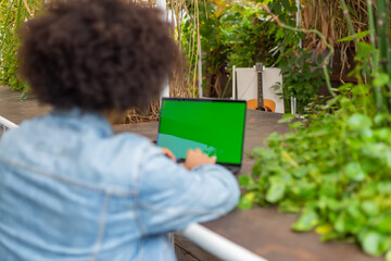 Young ethnic men , dressed in casual clothes, works on a laptop monitor with chroma key outdoors, in a green area in nature.Green open space free place to work,business, study, freelance in nature