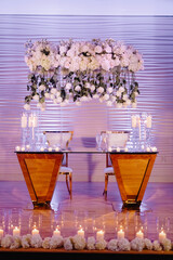 Wall Mural - Front view of festive glassed table of newlyweds decorated with fresh floral compositions and candles at wedding ceremony