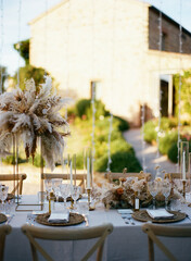 Wall Mural - Front view of elegant outdoor banquet with stylish decorations with dried flowers and golden details near cutlery and floral compositions at sunny day