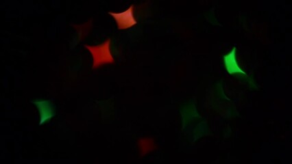Wall Mural - Red and Green Quadrilateral Bokeh Stars. Moving Christmas background or transition. Christmas stars twinkle and shimmer on a black background.