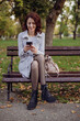 © Boris - Pretty laughing girl with smartphone has a good time in autumn weekend. Outdoor portrait of lovable trendy lady wear grey coat in october day.