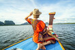 Travel tour by traditional long tail boat on tropical islands in Thailand. Woman sitting and relaxing, looking at the landscape.