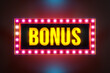Bonus - extra payment. Golden capital letters framed by illuminated light bulbs. Winning, casino, gambling, roulette, bingo,  entertainment events or reward and extra cash.