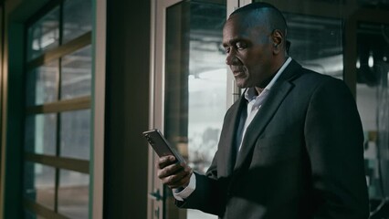 Serious focused businessman holding mobile phone chatting on internet browsing social network mature african man communicate with business client online writing electronic text message uses smartphone