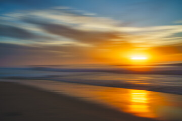 Wall Mural - Abstract seascape. Tranquil scene of empty sand beach at sunset. Golden waves, sun reflections, motion blur, copy space