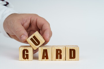 Poster - On a white surface, a man stacks cubes with the inscription - Guard