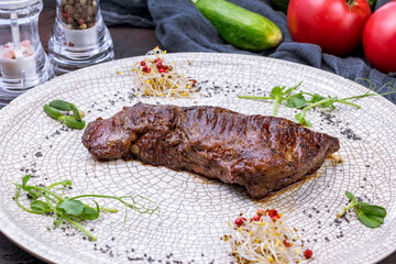 Wall Mural - roast beef Steak machete on grey plate on dark stone table side view